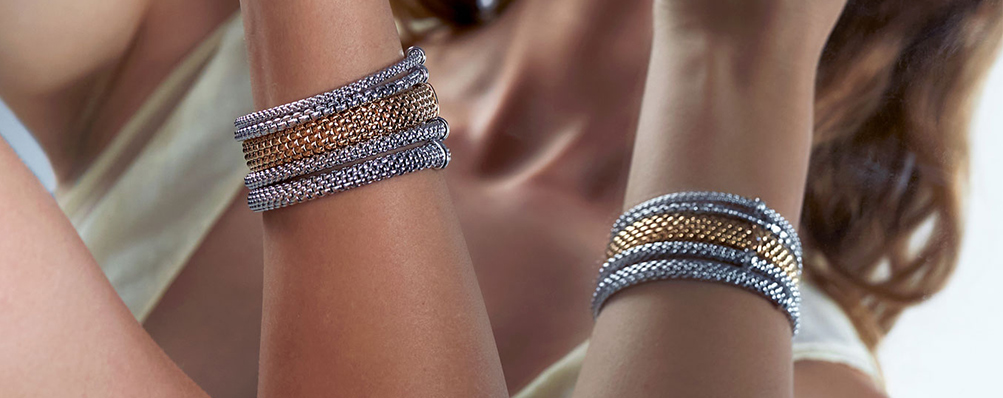 A collection of FOPE bracelets layered on arms