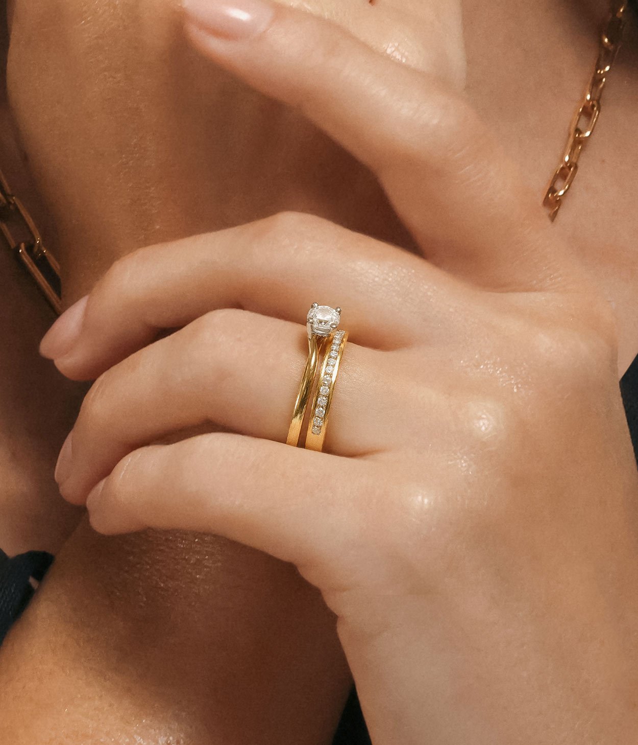 A model wearing an 18ct yellow gold diamond engagement ring, with a diamond-set wedding band.
