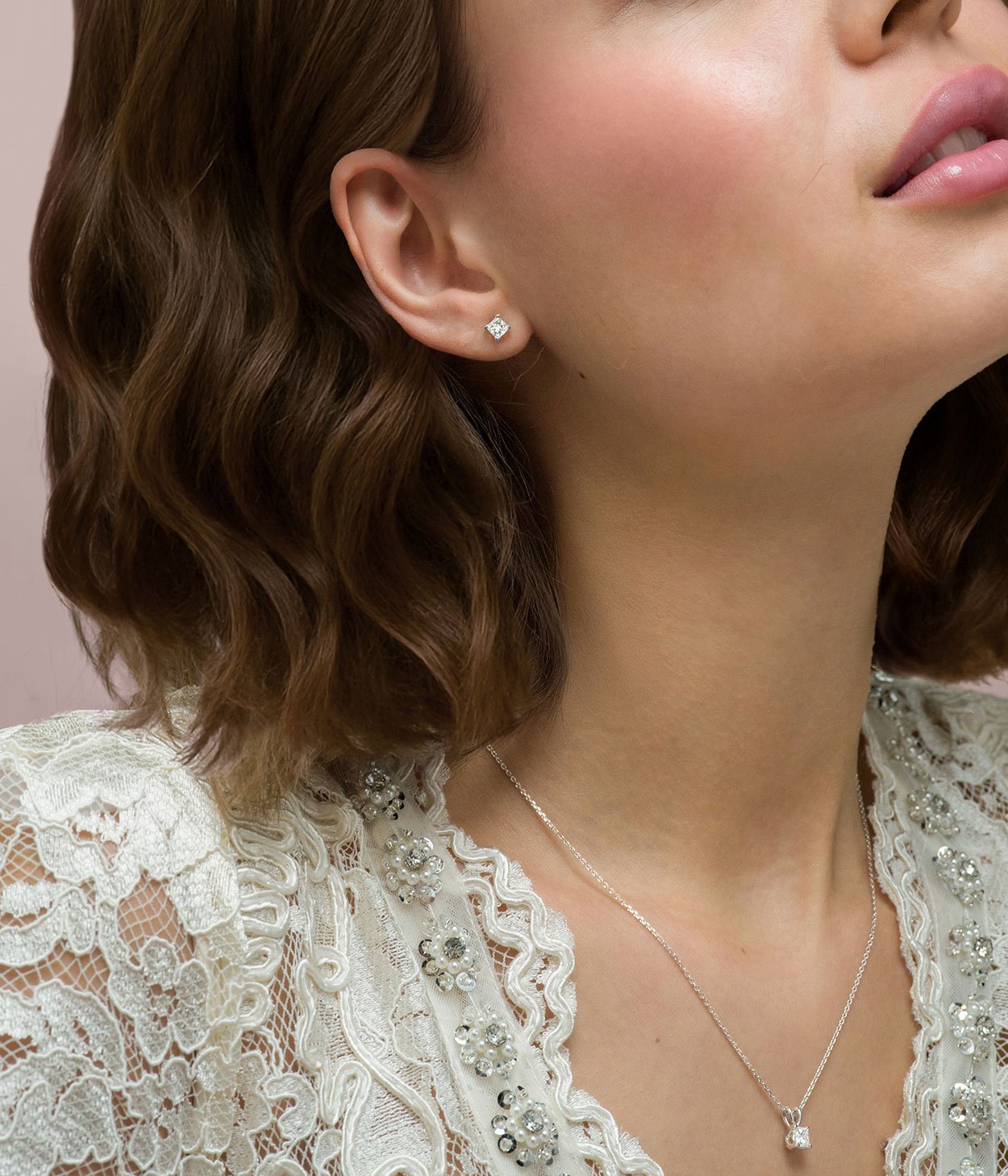 A young lady wearing the exclusive Laings Esme princess cut diamond stud earrings and matching pendant necklace.