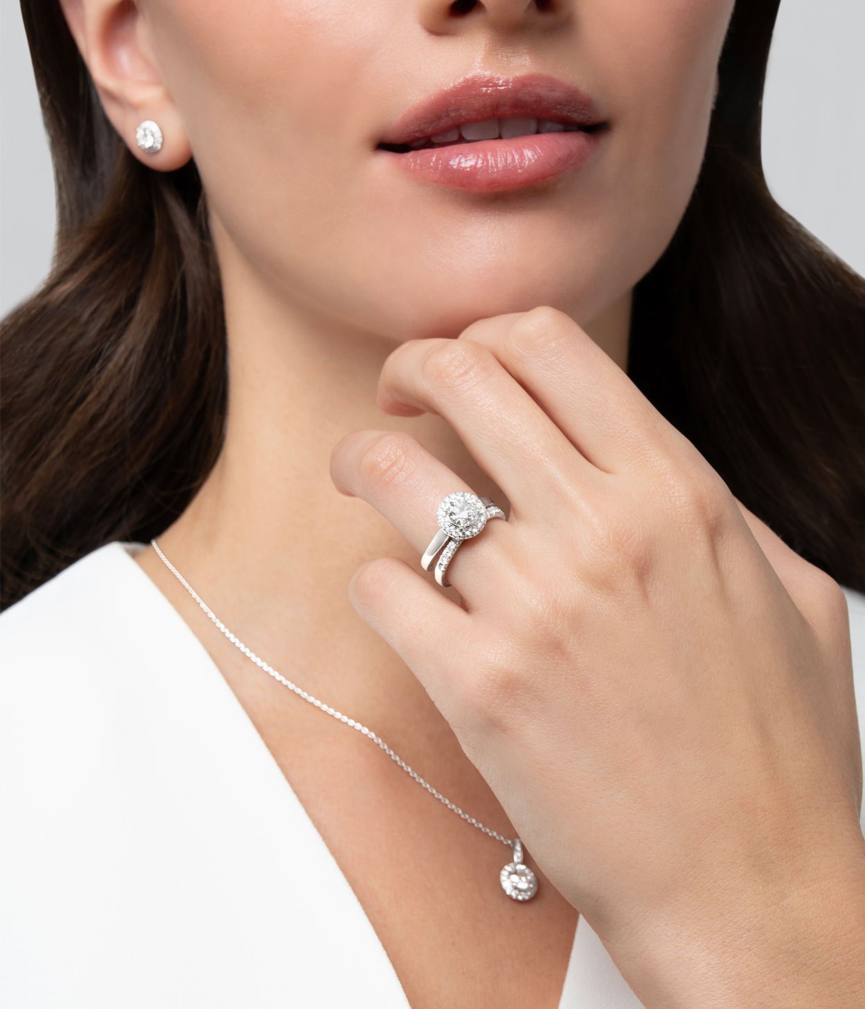 A lady wearing a platinum halo diamond engagement ring and diamond wedding band