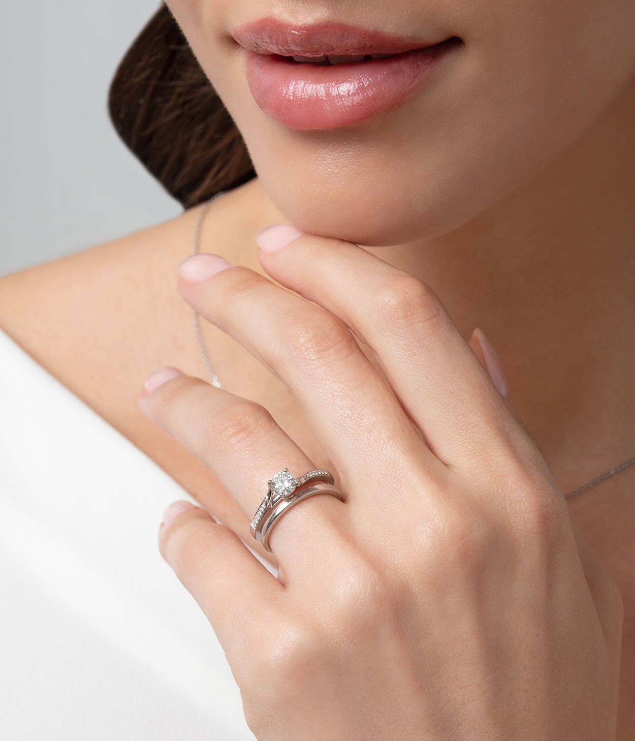 A lady wearing a solitaire diamond engagement ring with diamond shoulders and a plain wedding band