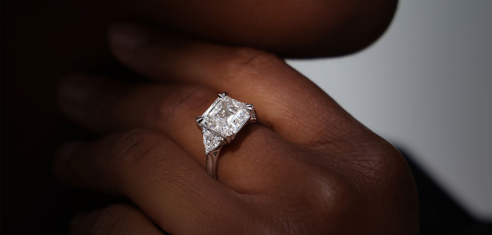 A model wearing a cushion cut laboratory grown diamond engagement ring, with two side stones set in platinum.