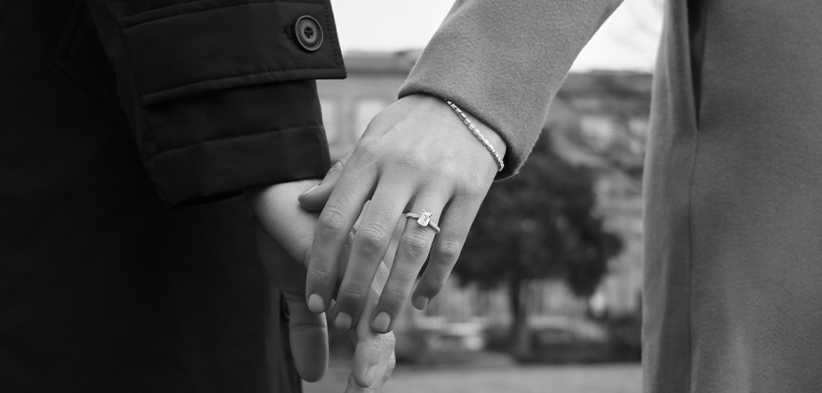 Newly engaged couple, holding hands with an emerald cut diamond engagement rings showing