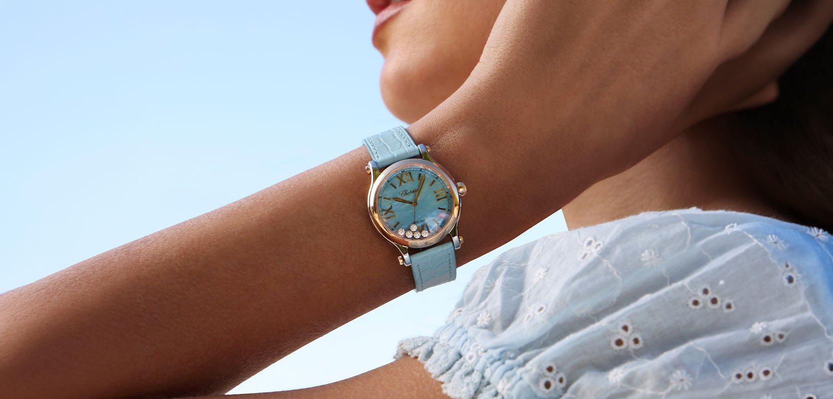 A woman wearing a chopard watch with a blue dial and dancing diamonds