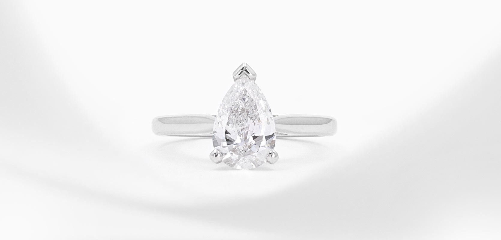 A pear cut diamond engagement ring with a platinum band and claws.