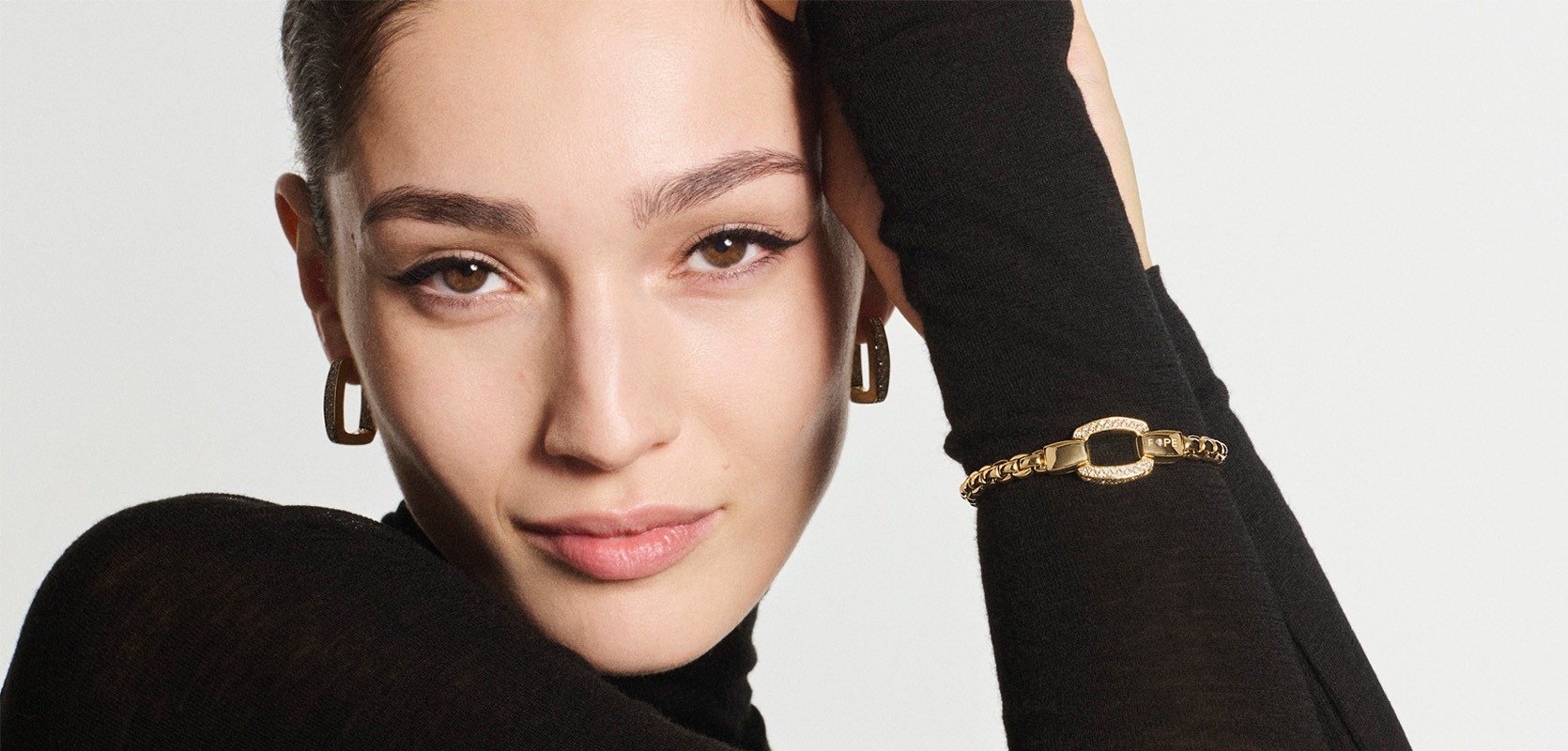 Five FOPE white and yellow gold bracelets on a woman wearing a white jumper, showing the different sizes available.