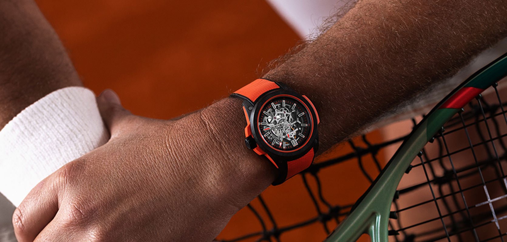 A man playing tennis whilst wearing the NORQAIN WILD ONES timepiece with striking orange accents and a black skeleton dial.