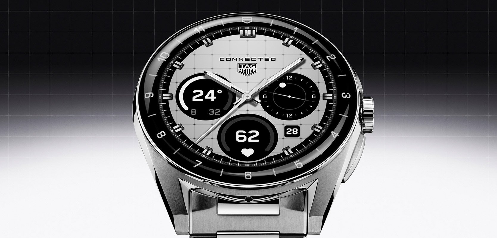 Close-up of a TAG Heuer Connected smartwatch with a silver case and black bezel, displaying a digital watch face with multiple dials on a monochrome grid background.