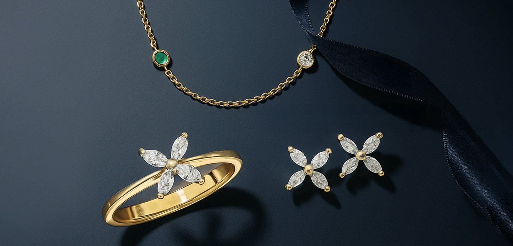 A selection of 18ct yellow gold jewellery from Laings, including a floral ring, stud earrings and a necklace featuring an emerald and diamond.