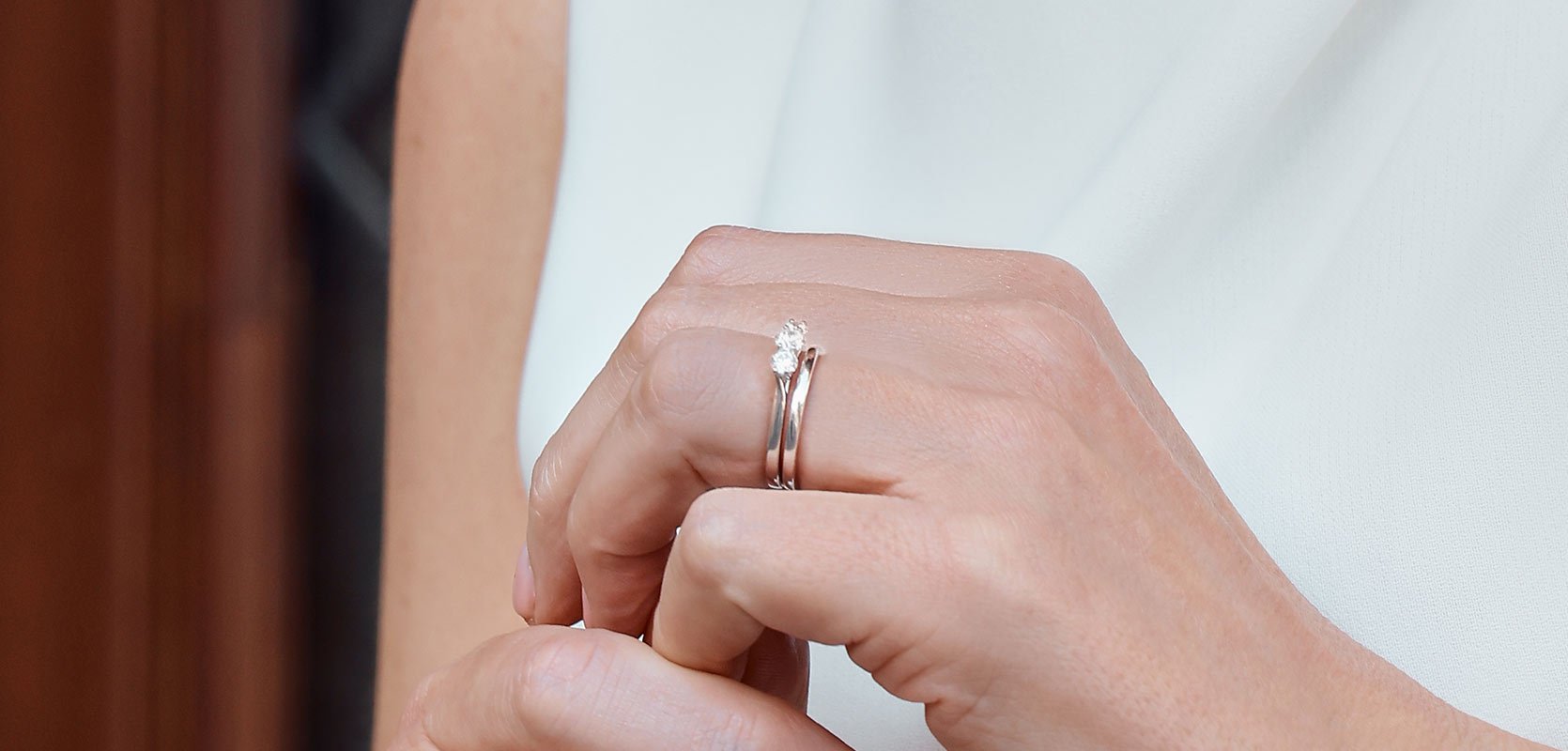 A mother of the bride wears her own three stone engagement ring and plain wedding band, both set in platinum.