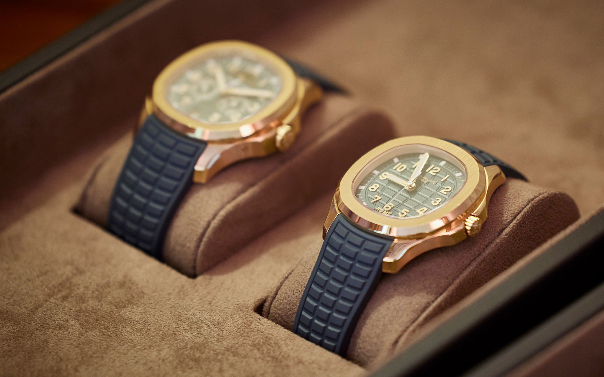 Close up of two Patek Philippe Aquanaut timepieces, both in navy and 18ct yellow gold