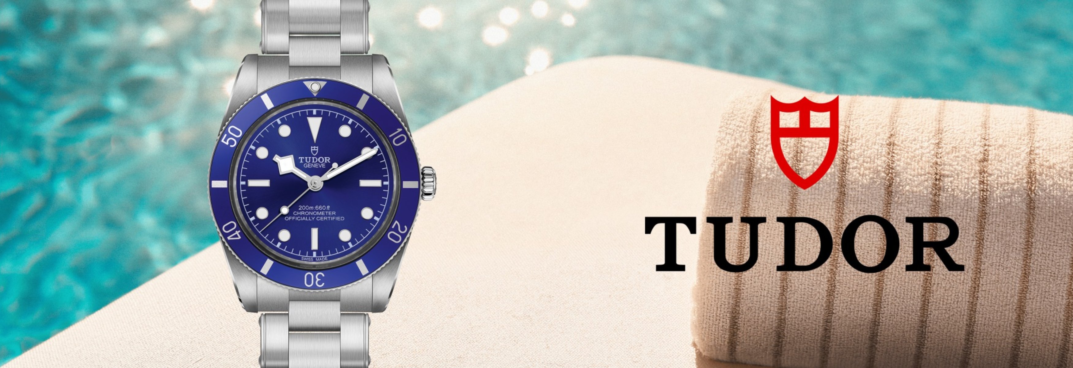 TUDOR Black Bay watch with a blue dial and bezel on a stainless steel bracelet, set against a poolside backdrop.