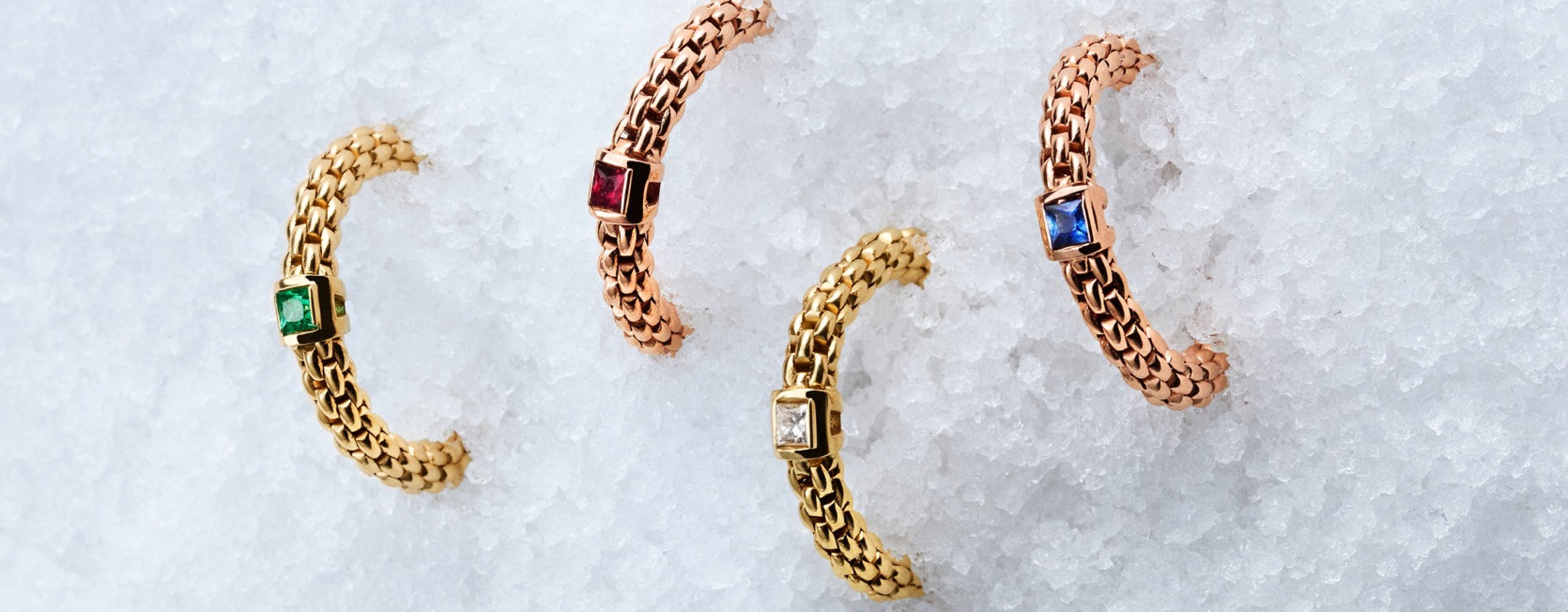 Four FOPE gold and gemstone rings in the snow; text on the right describes Flex'it Technology featuring hidden 18ct gold springs for comfort and elegance
