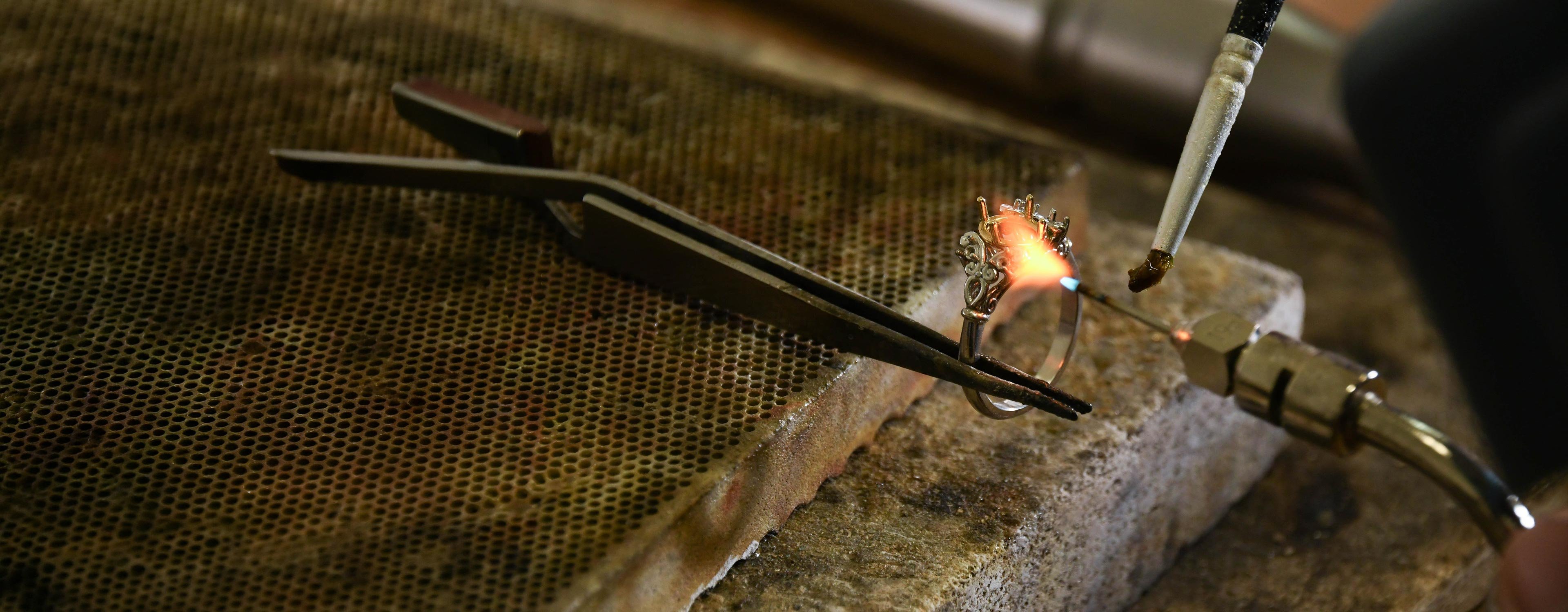 Craftsperson working on a yellow gold ring at a jewellery workshop bench