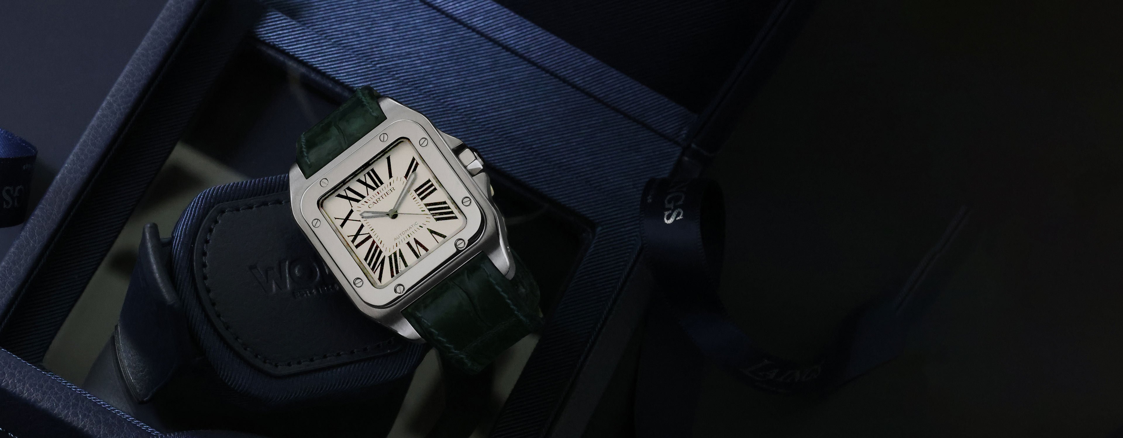 A pre-owned Cartier Santos watch with a green leather strap and white roman numeral dial.