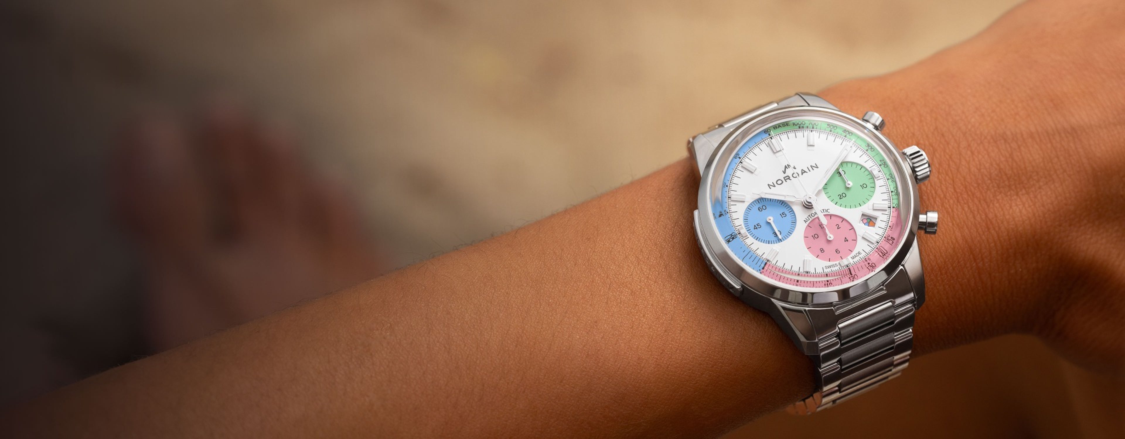 A ladies wrist with the NORQAIN 'Enjoy Life' watch that has a neapolitan dial and steel bracelets.
