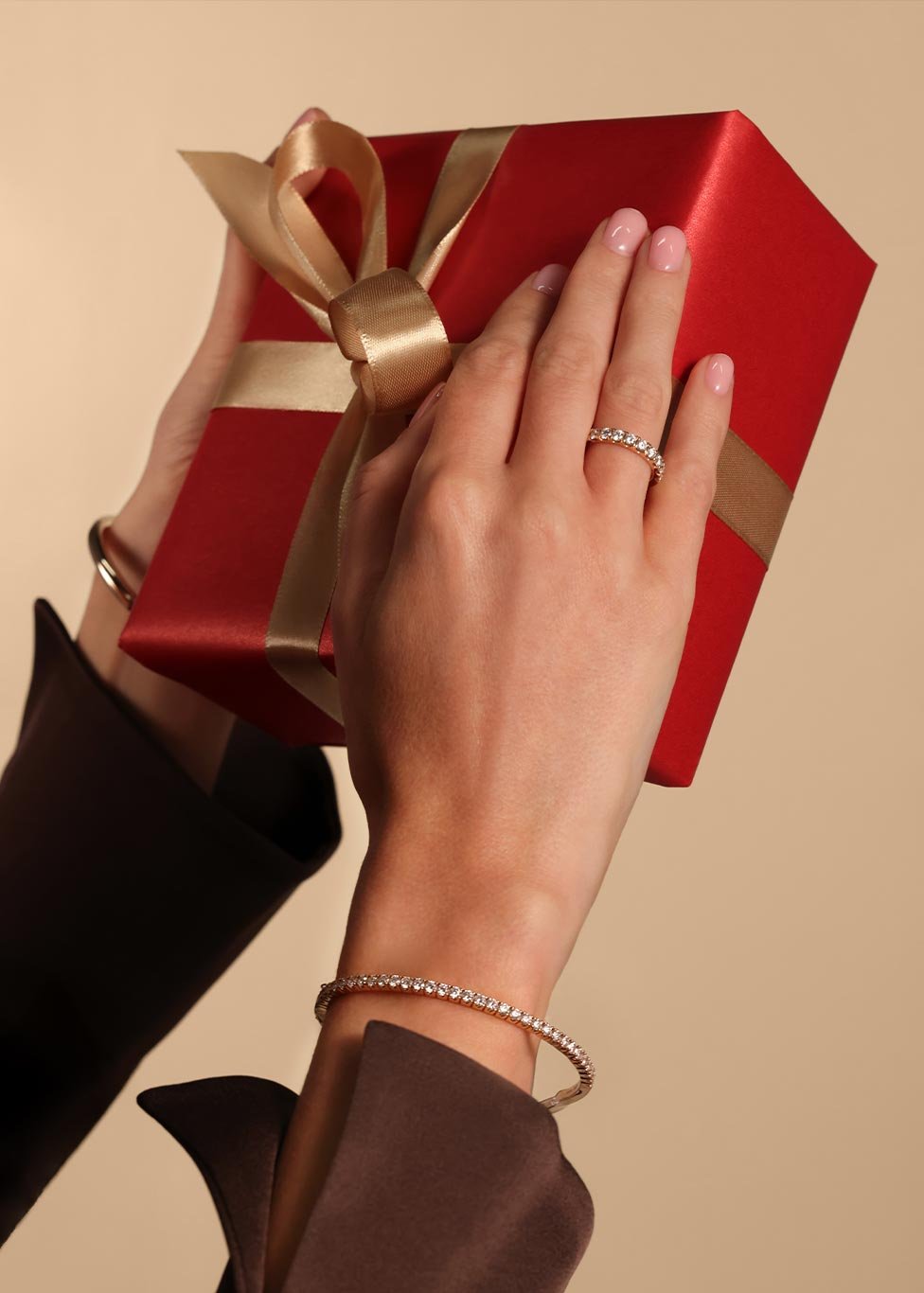 A ladies hands holding a jewellery gift box and wearing a diamond set featuring a diamond bangle and dress ring.
