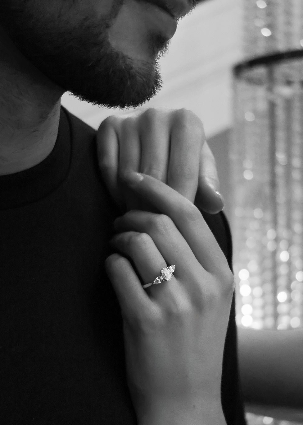 A woman wearing a three stone diamond engagement ring. The image is in black and white.