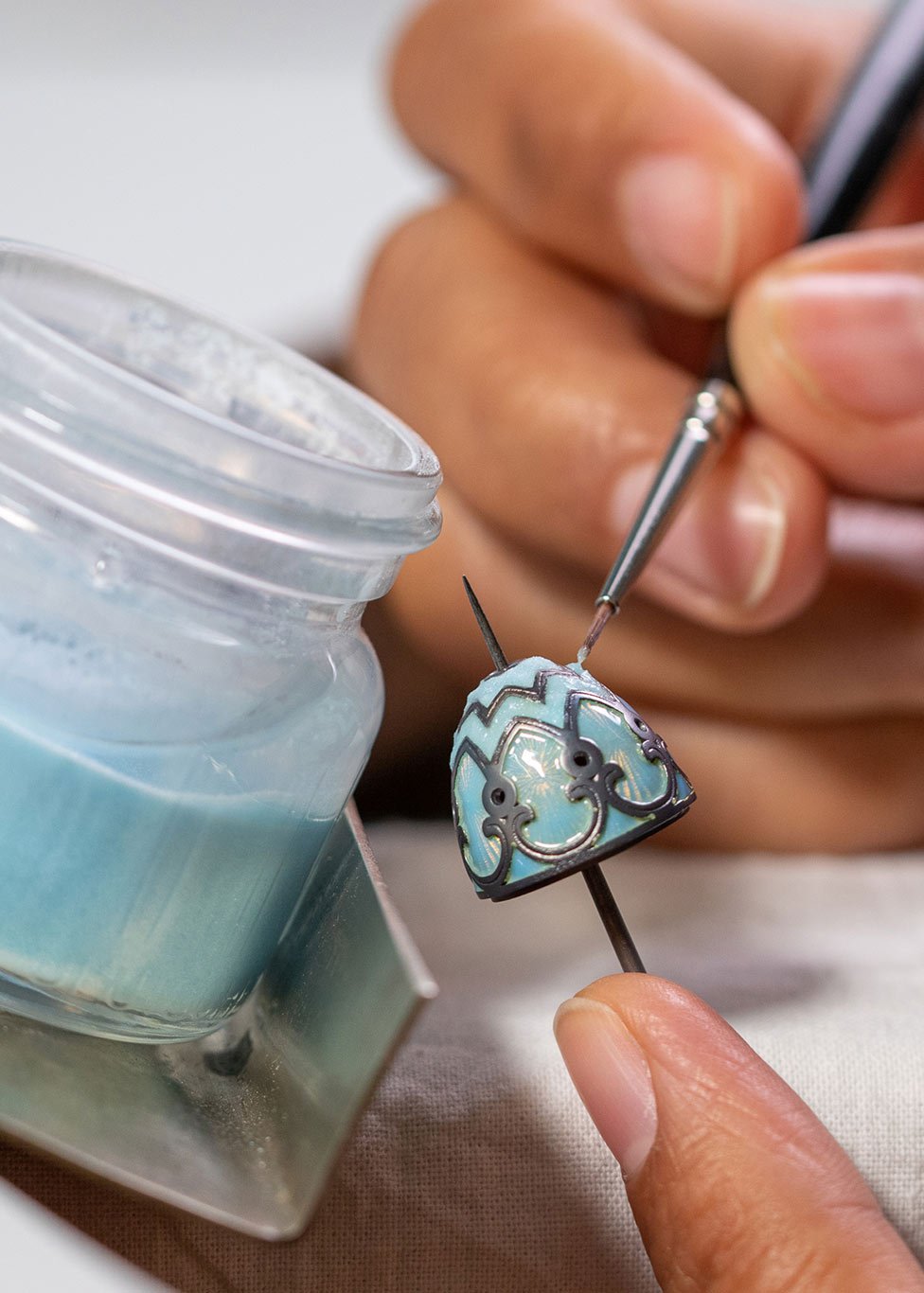 A goldsmith works on enamelling a Faberge pendant