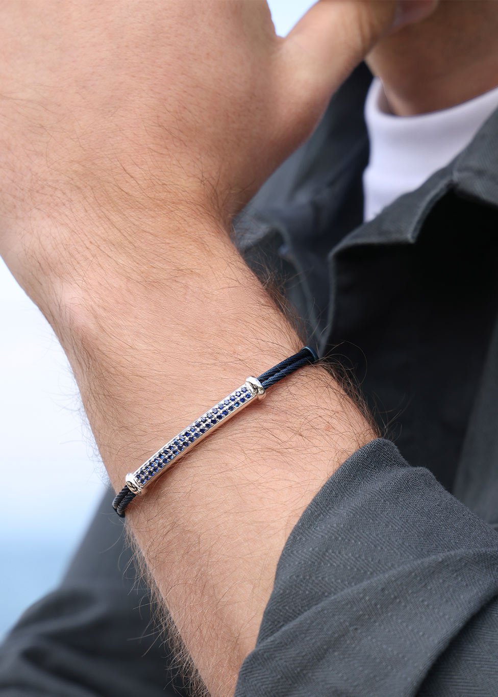 A man wears a titanium bracelet with a blue sapphire bar detail.
